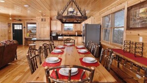 Ein Holzblockhaus-Interieur mit einem langen Esstisch, gedeckt für sechs Personen, umgeben von Holzkästen.