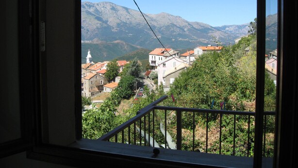 Blick aus einem Fenster auf eine Stadt mit Gebäuden und Bergen.