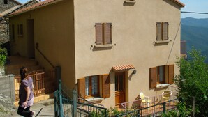 Ein zweistöckiges Gebäude mit einer beige farbenen Fassade, Holzhörnern und einem kleinen Balkon.