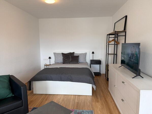 Une chambre à coucher comprenant un lit, des tables de chevet, une télévision, un canapé et une commode.