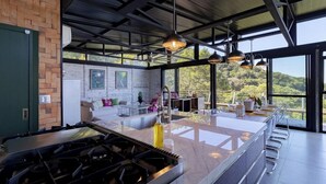 Cozinha moderna com uma ilha grande, eletrodomésticos de aço inoxidável e vista para o exterior.