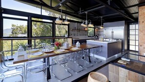 Uma cozinha moderna com uma ilha grande, eletrodomésticos de aço inoxidável e janelas amplas com vista para o exterior.
