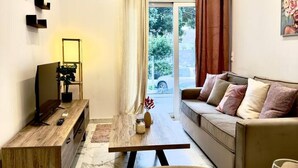 Una sala moderna con un sofá, una mesa de centro y un televisor sobre un soporte de madera. Hay un comedor con platos y cubiertos.