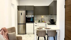 Una cocina moderna con horno empotrado, refrigerador y comedor con mesa y sillas.