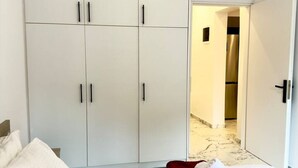 Una habitación de hotel con cama, armario y baño a la vista a través de una puerta abierta.