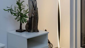 A modern living room with a white cabinet, a tall floor lamp, and a potted plant.