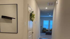 Un pasillo con suelo de madera, una puerta decorada con un adorno, un perchero y un cuadro en la pared.