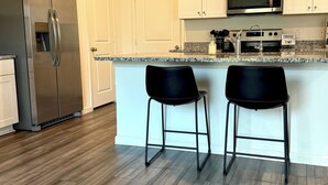Una cocina moderna con armarios blancos, electrodomésticos de acero inoxidable y suelo de madera.