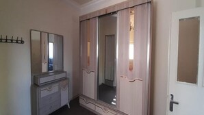 A bedroom with a large wardrobe, a dresser, and a mirror. - Homey Apt in Jerash w/ City-View. Explore Jerash Ruins from this Spacious Apt (Jerash)