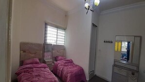 A bedroom with two beds, a dresser, a mirror, and a window with blinds. - Homey Apt in Jerash w/ City-View. Explore Jerash Ruins from this Spacious Apt (Jerash)