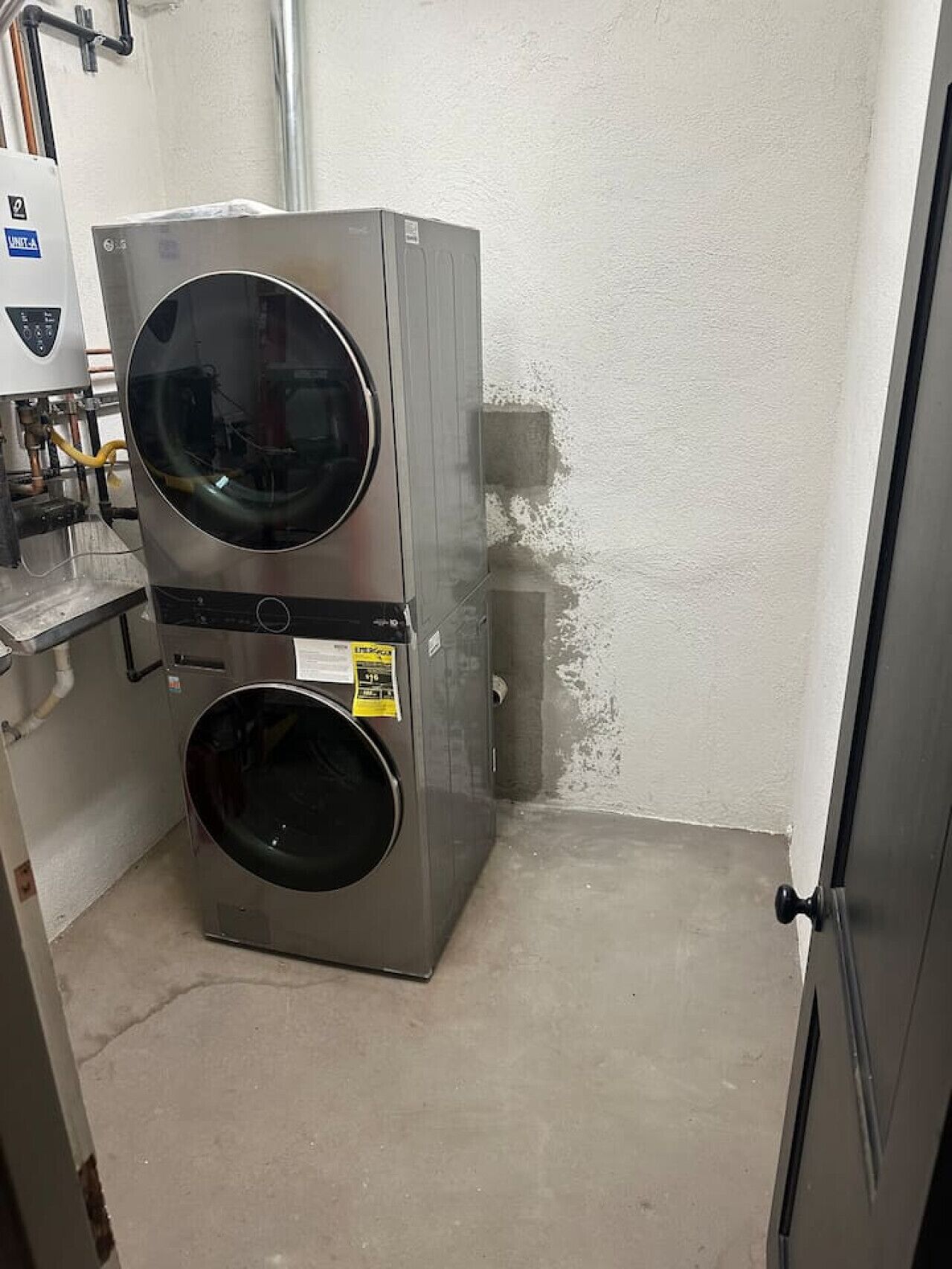 Eine kompakte, wendige Waschmaschine in einem kleinen Raum mit Betonboden und schlichter Wand.