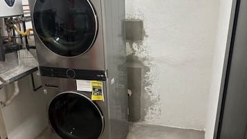 Eine kompakte, wendige Waschmaschine in einem kleinen Raum mit Betonboden und schlichter Wand.