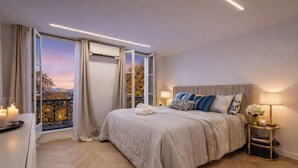 Un dormitorio con una cama grande, una mesita de noche con lámpara y vistas al exterior a través de una puerta corredera.
