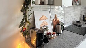 Una cocina moderna con armarios blancos, una encimera con cafetera y una guirnalda decorativa.