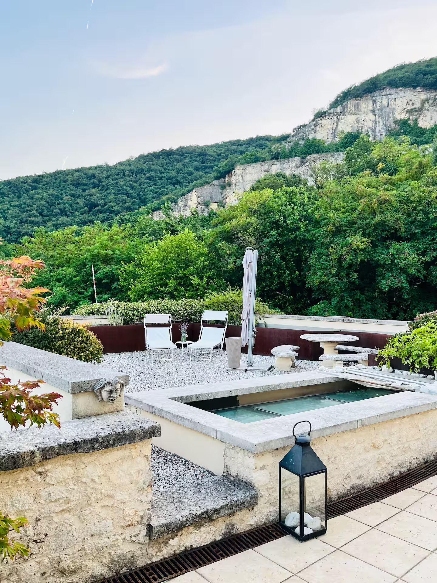 A rooftop terrace with a pool, seating area, and a view of a mountainous landscape.