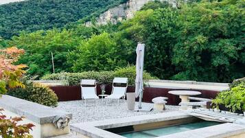 A rooftop terrace with a pool, seating area, and a view of a mountainous landscape.