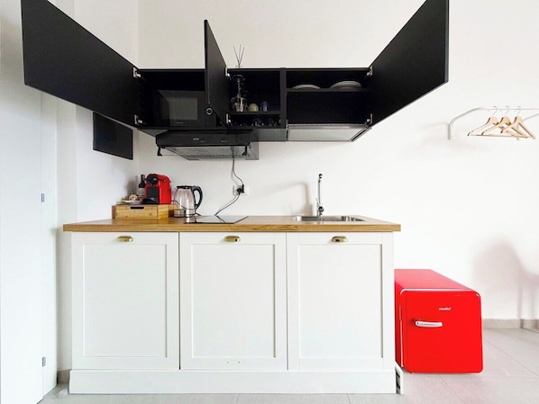 A kitchen with a microwave, coffee maker, and a red appliance on the counter.