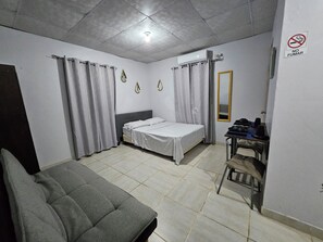 A bedroom with a bed, a chair, a desk with a mirror, and a 'No Smoking' sign. - Apartamento tipo estudio Lyon, en David, cerca de varios centros comerciales! (David)