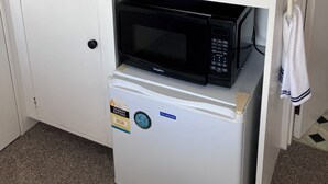 A compact kitchenette with a sink, a coffee maker, a kettle, and a microwave.