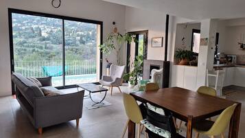 Un salon moderne comprenant un canapé, une table à manger, des chaises et donnant sur un balcon avec une balustrade.