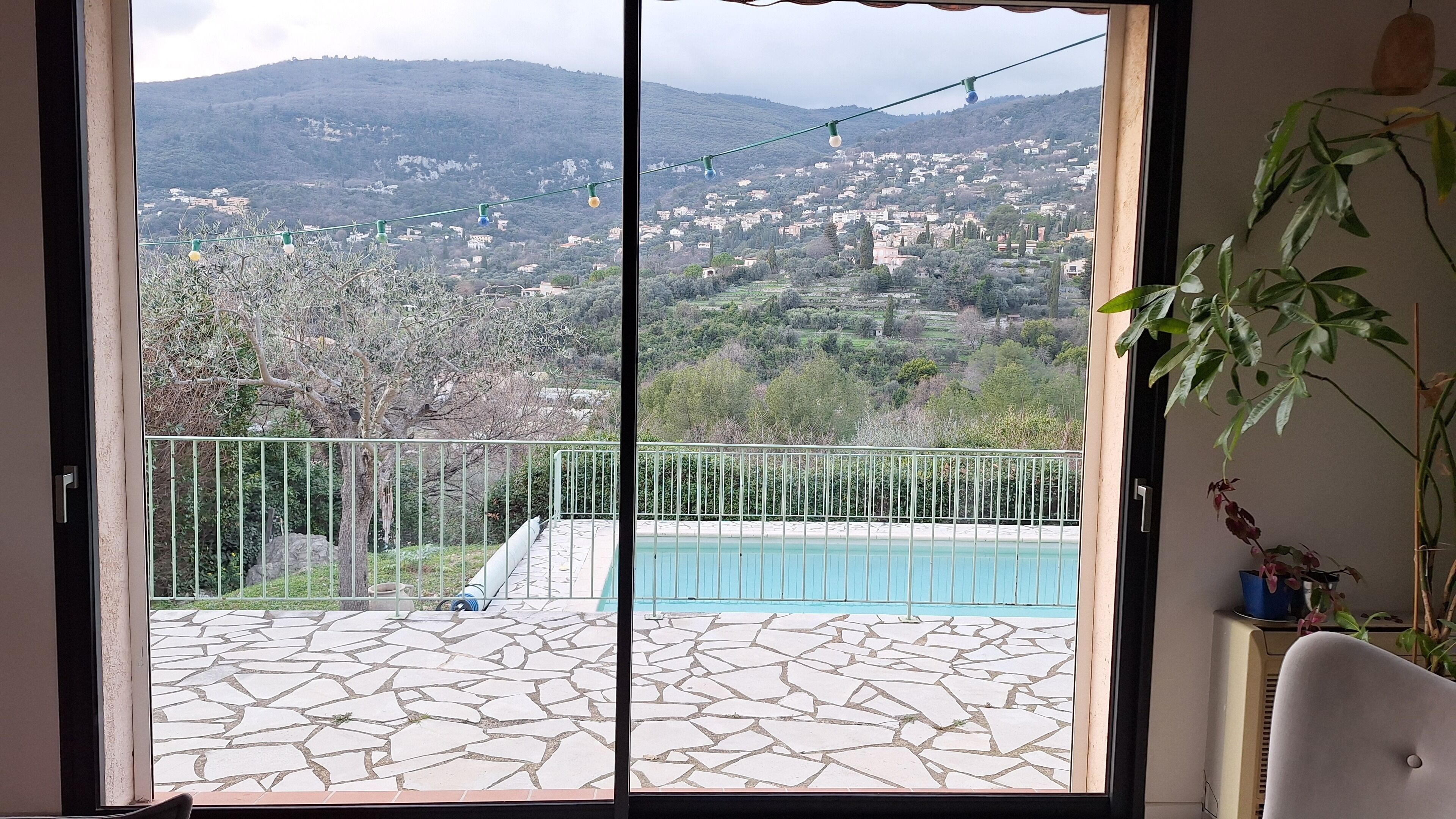 Une chambre avec vue sur un paysage montagneux, une piscine et un balcon doté d’une balustrade.