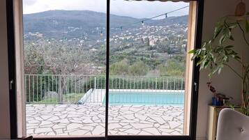 Une chambre avec vue sur un paysage montagneux, une piscine et un balcon doté d’une balustrade.