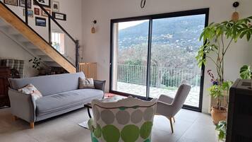 Un salon moderne avec un canapé gris, une table basse à motifs et une vue sur un balcon doté d’une balustrade.