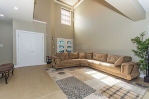 A living room with a beige sectional sofa, a bench, and a large decorative rug.