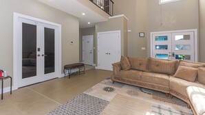 A spacious living room with a beige sofa, a patterned rug, and a staircase leading to a balcony. - Executive lodging (Edmonton)