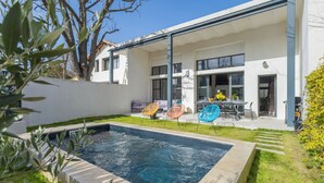 Een modern huis met een zwembad, terras en een verzorgde tuin.