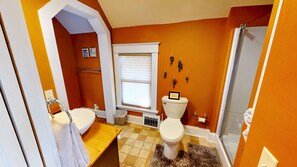 Een badkamer met toilet, wastafel, douche en een raam.