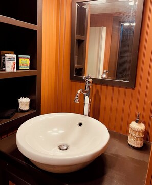 A bathroom with a white sink, a mirror, and shelves with toiletries. - Cottage on the Rock, a spacious 5-bedroom house on the Rock River (Fort Atkinson)