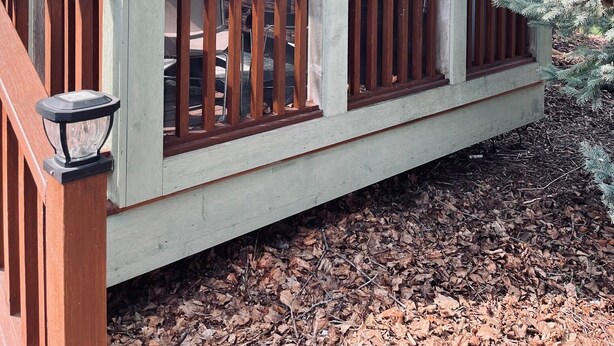Une maison avec un porche, des balustrades en bois et une grande fenêtre.