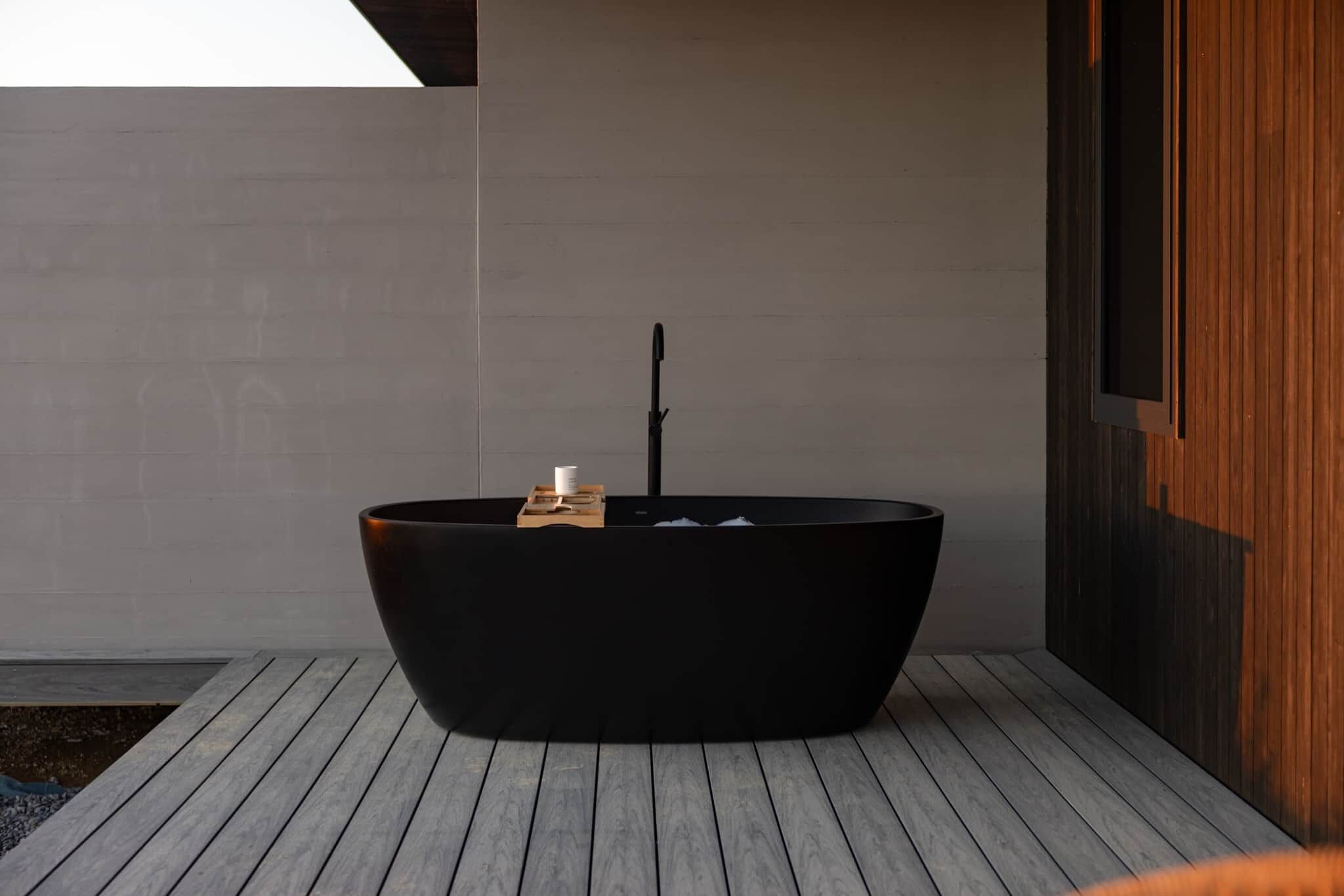 Un baño moderno con una bañera independiente, una mesita de madera y un perchero para toallas.