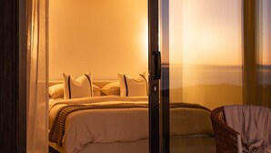 A bedroom with a bed, pillows, and a chair, featuring a sliding glass door and a view of the outdoors. - The Hide Kapiti Accommodation (Maungakotukutuku)