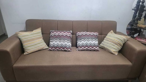 Ein braunes Sofa mit zwei gemusterten Kissen und einem kleinen runden Tisch.