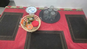 Ein Tisch mit rotem Tischlaken, zwei schwarzen Platzsets, einem Snackkorb, einem kleinen Teller mit Beilagen und einem Gläser-Set.