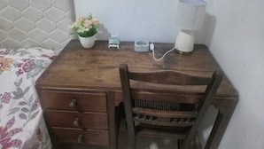 Ein Holztisch mit Stuhl, Lampe, einer kleinen Pflanze und einer Steckdose.