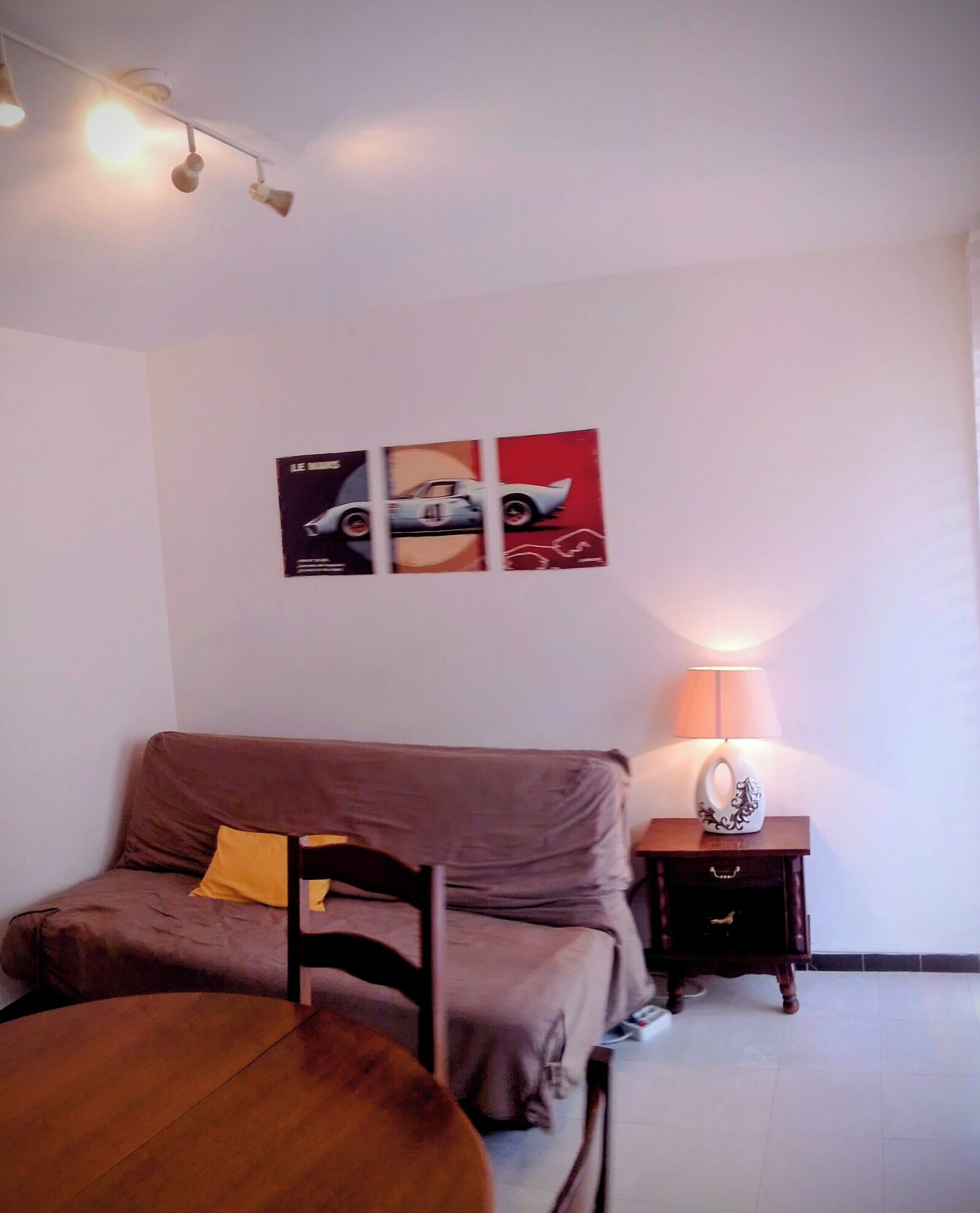 A bedroom with a bed, a bedside table with a lamp, and wall art.