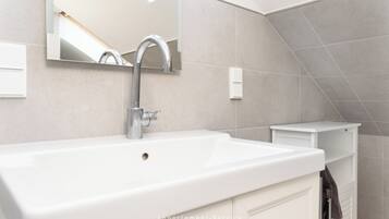 Een moderne badkamer met een grote witte wastafel, een spiegel en een handdoekhouder.