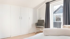 A bedroom with a large bed, a chair, and a wardrobe. - Vacation apartment MeerZeit (Stein)