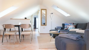 A modern living room with a dining area, a sofa, and a large mirror. - Vacation apartment MeerZeit (Stein)