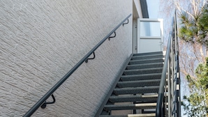 A staircase with a metal handrail leading to a white door. - Vacation apartment MeerZeit (Stein)