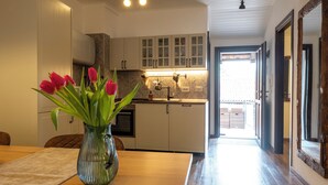 Una cucina con mobili bianchi, un tavolo da pranzo con un vaso di tulipani e vista sull'area pranzo adiacente.