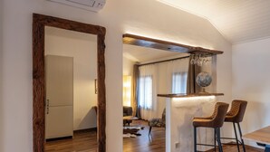 Una cucina moderna con pavimento in legno, un grande specchio e un angolo bar con due sgabelli.