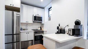 A modern kitchen with stainless steel appliances, a microwave, a kettle, and a coffee maker. - Soho 2 bedroom stylish apartment (New York)