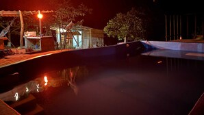 Ein Nachtblick auf einen Poolbereich mit einem kleinen Gebäude und Bäumen.