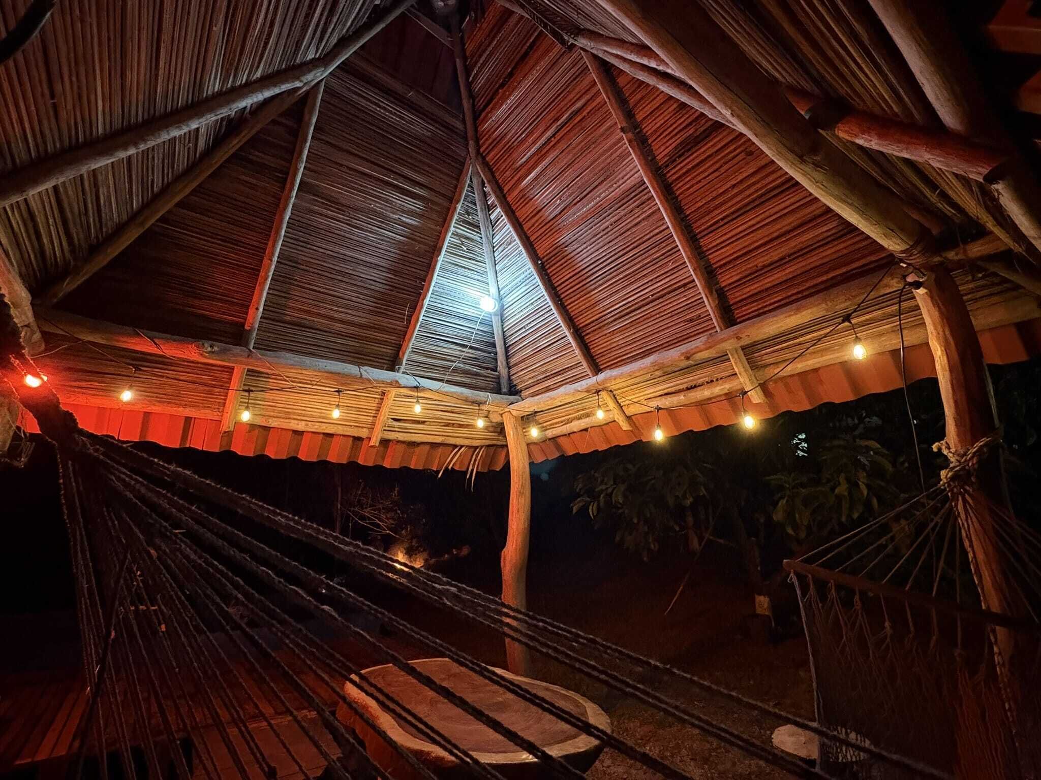 Un espace extérieur abrité, doté d’un hamac, de poutres en bois et de guirlandes lumineuses.