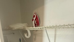 Ein kleiner Waschbereich mit Wäscheständer, Bügeleisen und Besen.