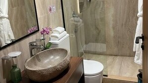 A modern bathroom with a stone sink, a glass shower enclosure, and a large mirror. - The Nomad Pyramids Luxury Wing (Giza)